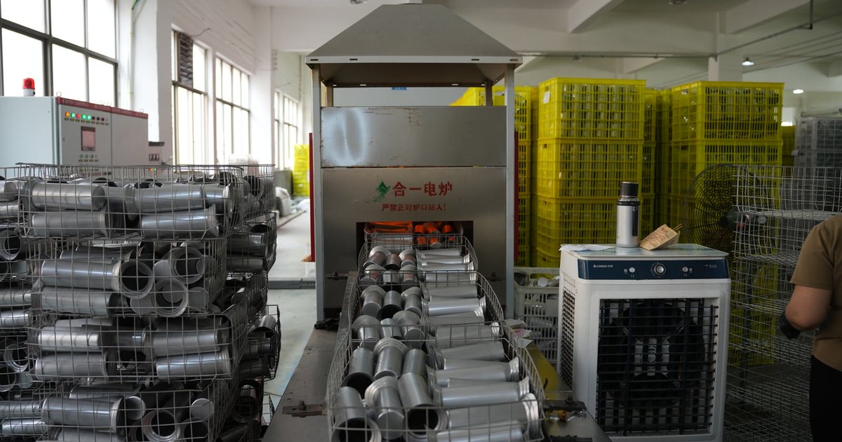 Stainless steel tumbler body blanks in wire baskets on the conveyor into an electric furnace at a Yongkang vacuum drinkware factory