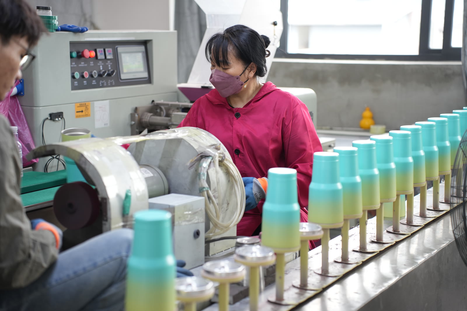 Worker polishing gradient powder coated tumblers on production line